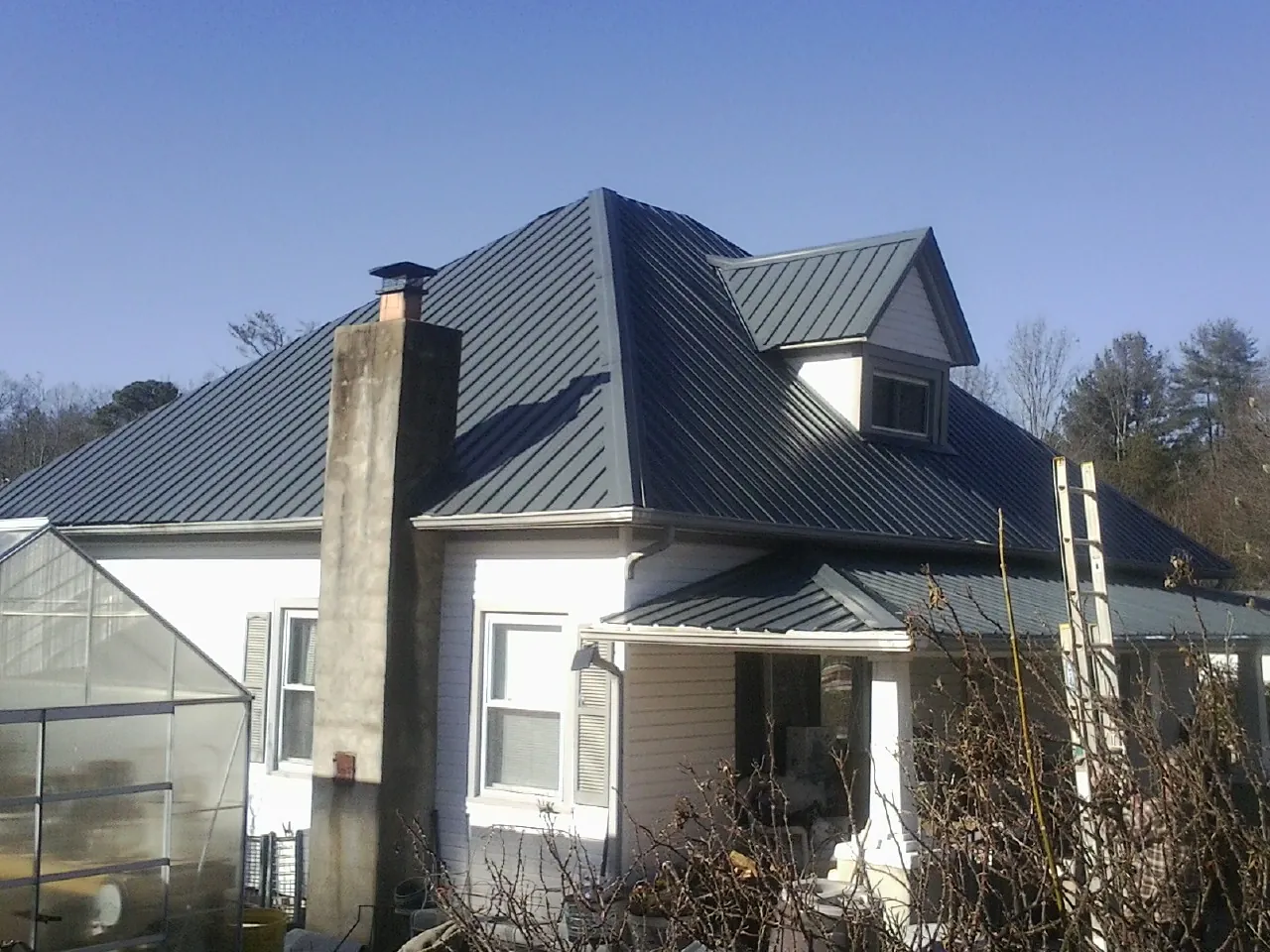Dark blue standing seam metal roof on a white farmhouse with dormer — Slate & Tile Roof Repair by Roofing Brothers in Paulden