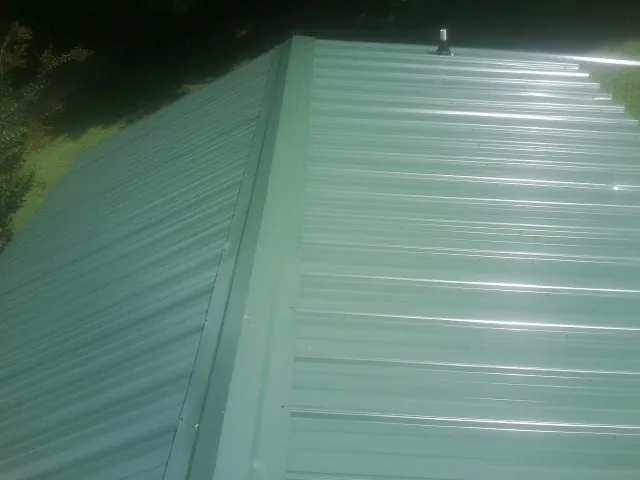 New green metal panels meeting at the ridge of a roof — Flat Roof Repair work by our crew in Paulden