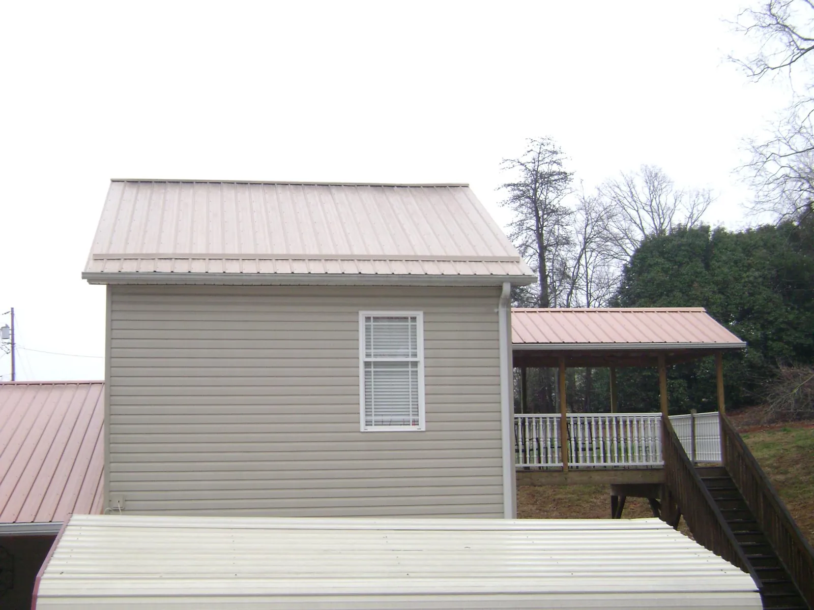 Tan metal roofs on a two story addition and attached porch, from a Roof Replacement job in Paulden
