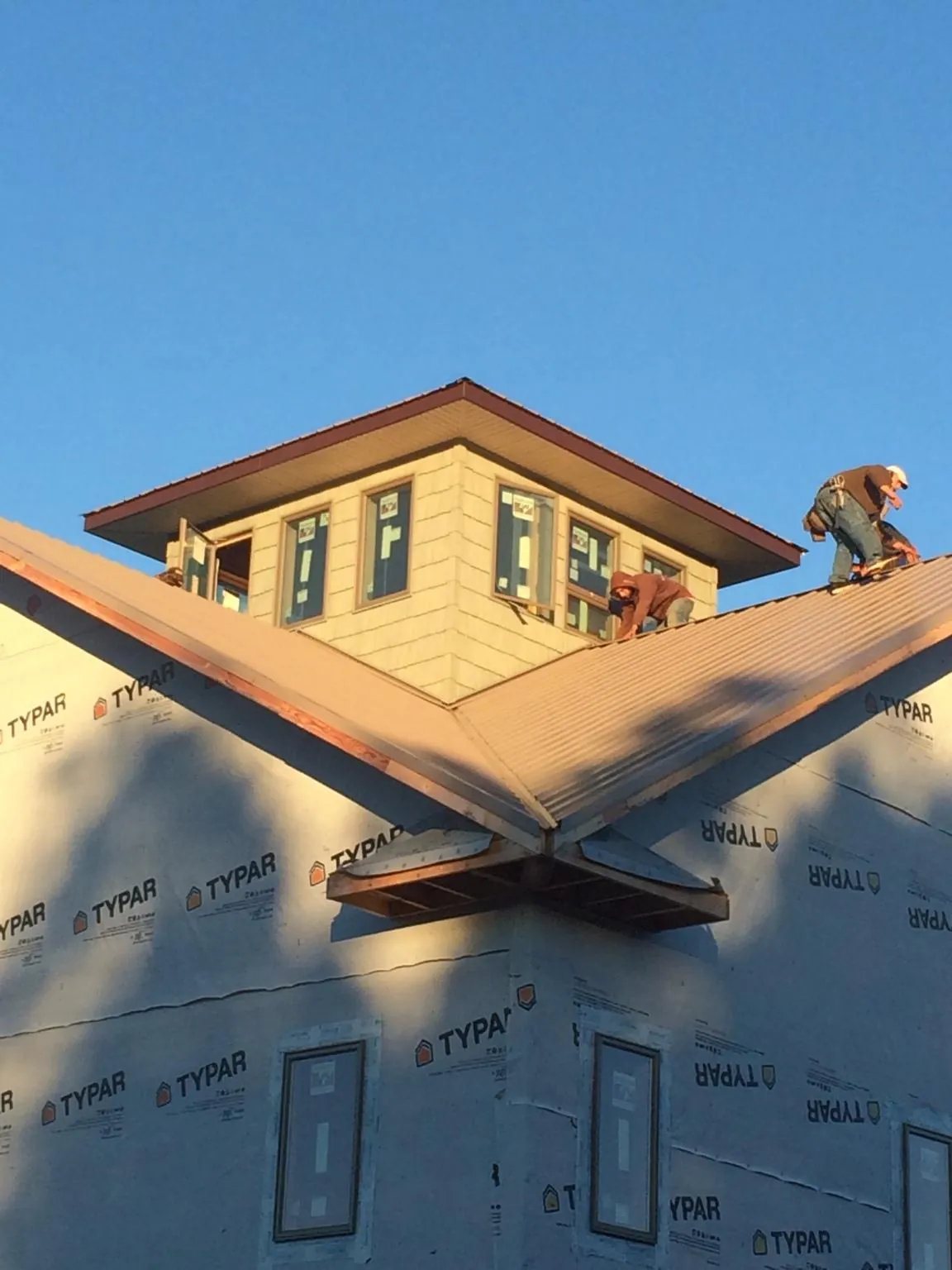 Roofers working around a rooftop cupola on a new metal roof at sunset — Roof Waterproofing in Paulden by Roofing Brothers